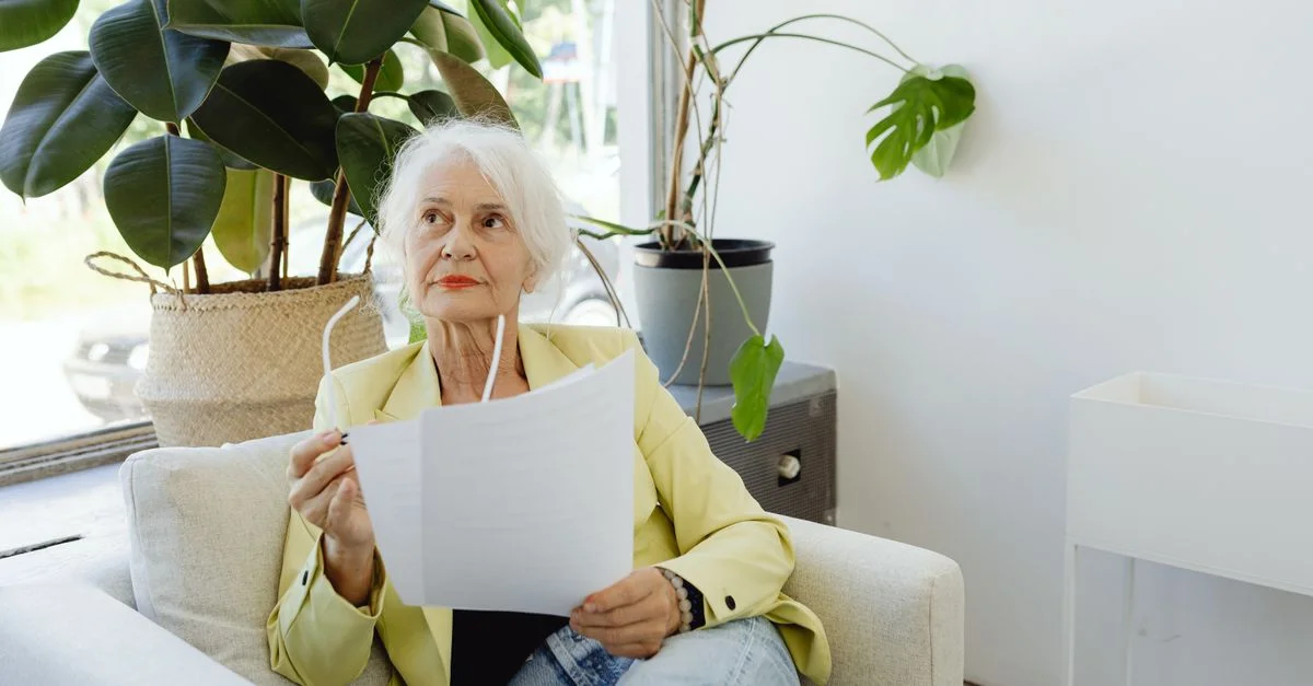Femme senior dans un cadre décontracté examinant des documents à l'intérieur.