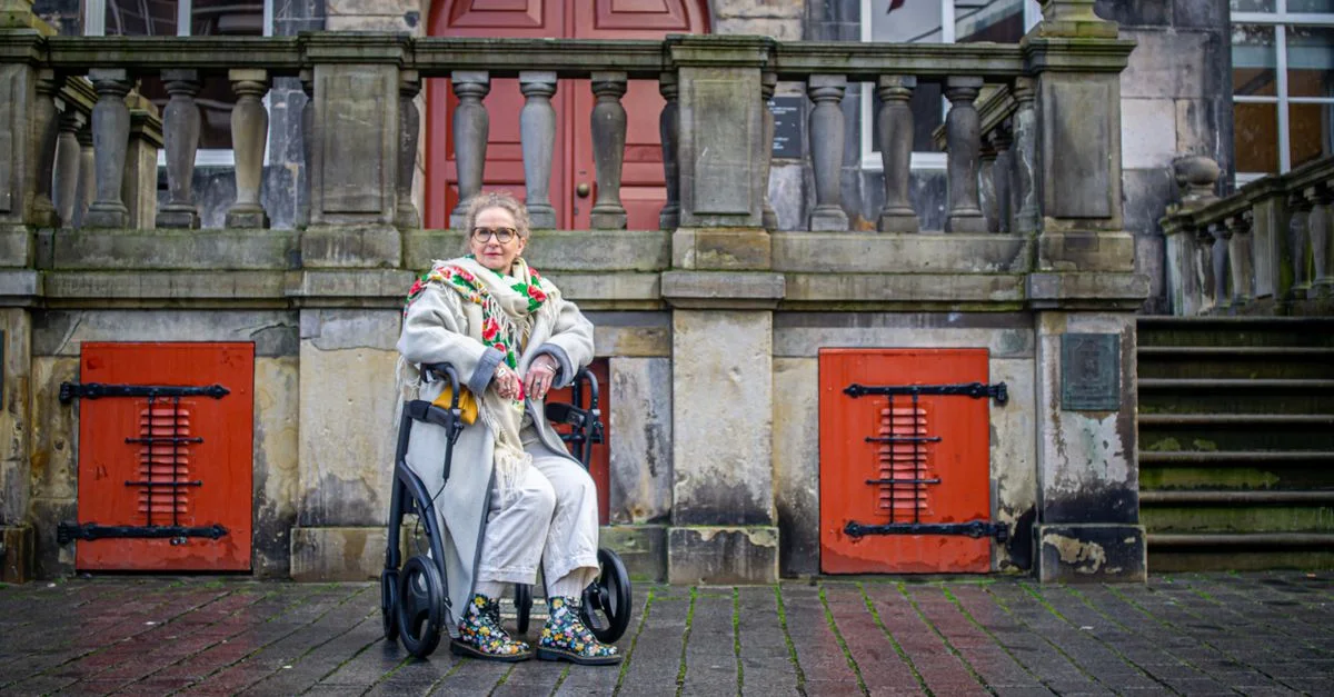 Élégante femme senior assise en extérieur avec un déambulateur, embrassant la mode urbaine.