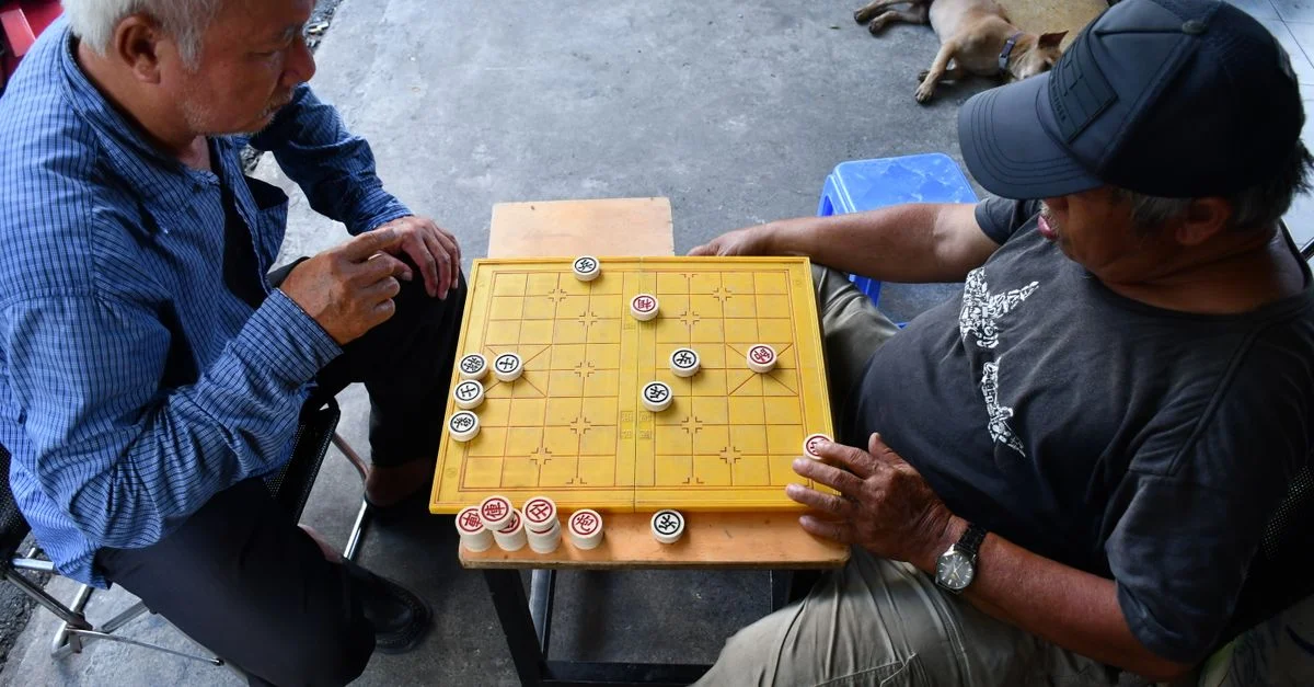 Des hommes seniors jouant à un jeu de société traditionnel en plein air à Ho Chi Minh-Ville, Vietnam.
