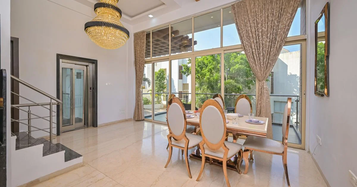 Salle à manger élégante avec un lustre, de grandes fenêtres et des meubles stylés dans une maison moderne.