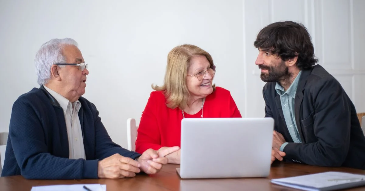 Un couple âgé ayant une consultation avec un conseiller professionnel dans un cadre intérieur lumineux.