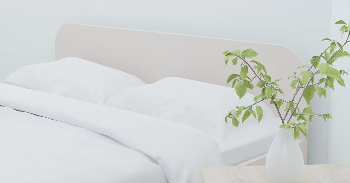 Chambre moderne lumineuse et aérée avec linge de lit blanc et un vase de verdure sur une table en bois.