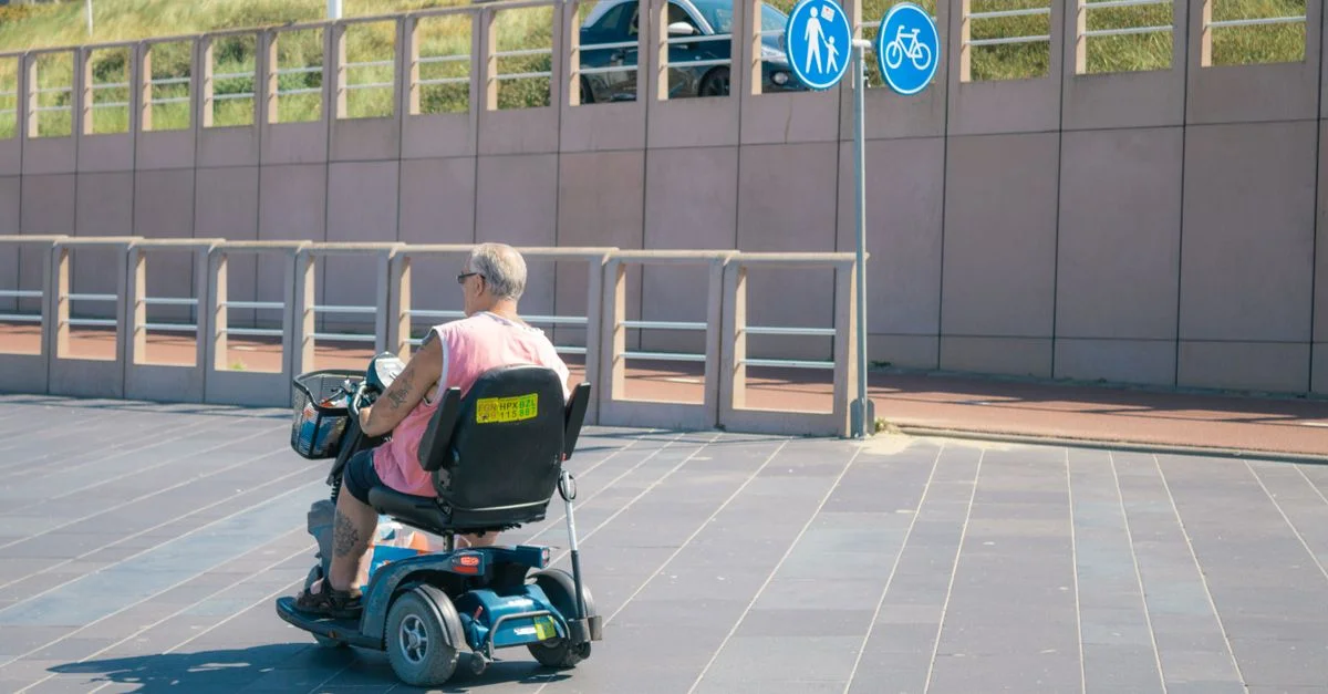 Un homme senior roule sur un scooter de mobilité électrique par une journée ensoleillée, symbolisant l'indépendance et un style de vie actif.