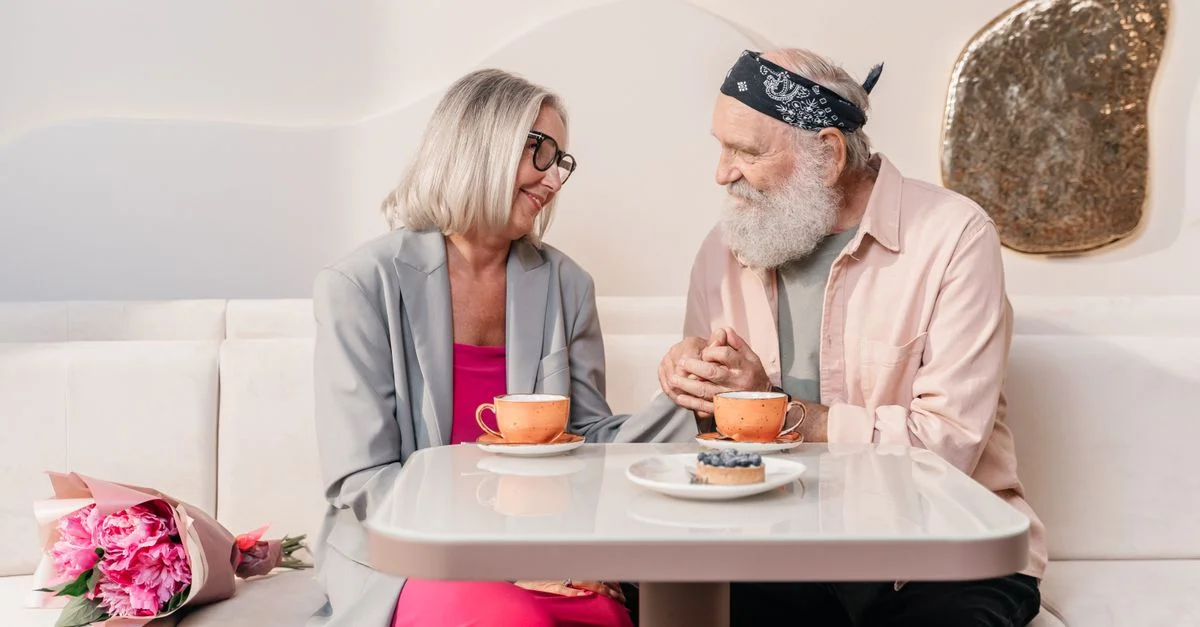 Un couple âgé partageant un moment romantique autour d'un café, se tenant par la main dans un café confortable.