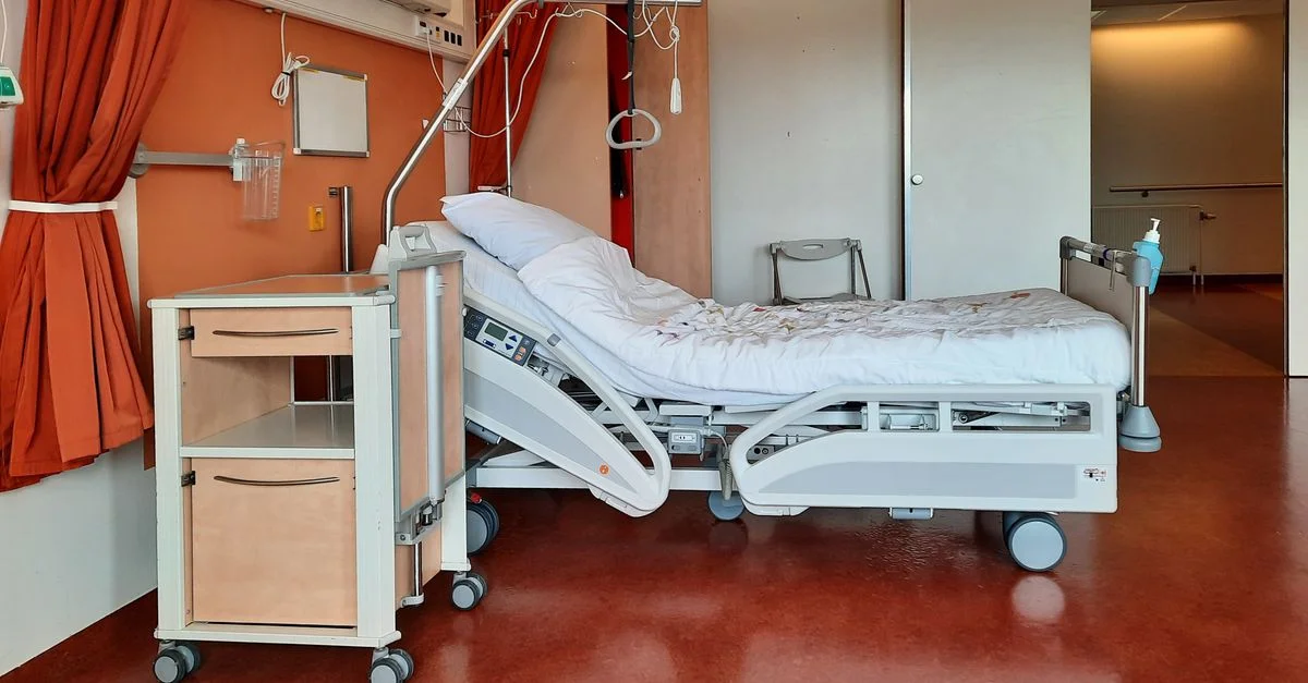 Une chambre d'hôpital propre et moderne équipée d'un lit ajustable et d'un matériel médical.