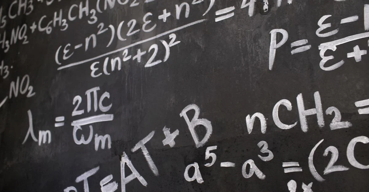 Vue rapprochée d'un tableau noir rempli d'équations et de formules mathématiques complexes.