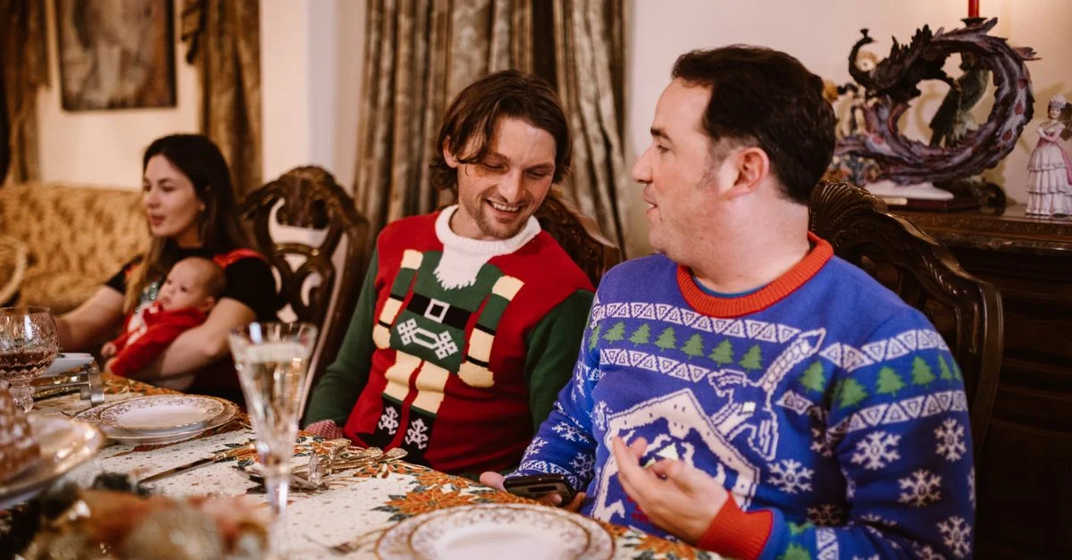 Famille profitant d'un repas de fête en pulls de Noël, capturant la chaleur et la joie de la saison festive.