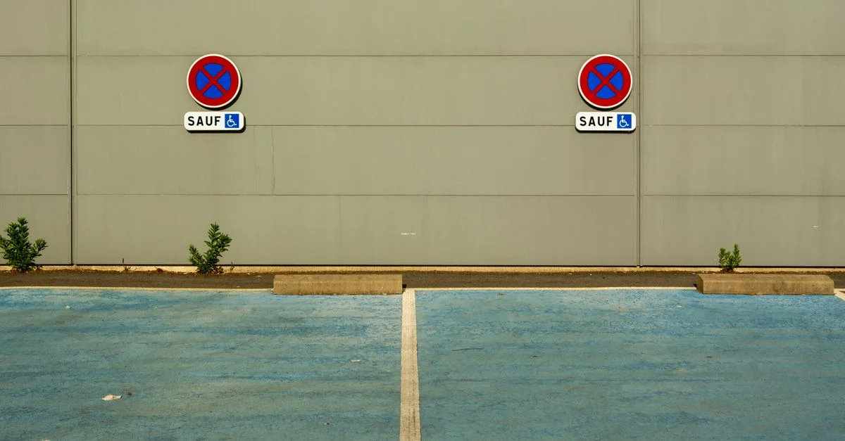 Deux places de stationnement pour personnes handicapées bleues avec des panneaux indiquant qu'il est interdit de stationner sauf pour les véhicules de personnes handicapées.