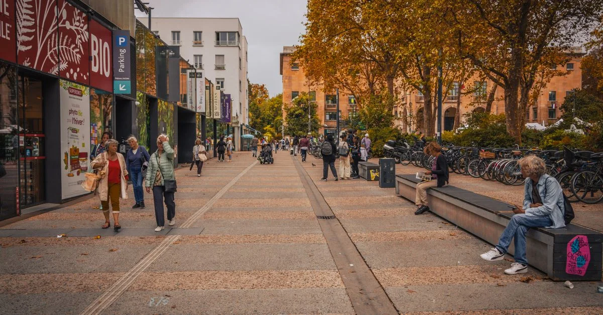 Une scène de rue urbaine vibrante avec des gens marchant et des vélos garés par une journée ensoleillée d'automne.