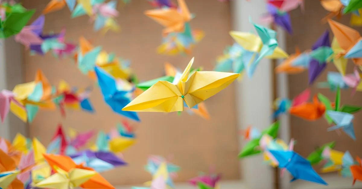 Grues en origami colorées suspendues à l'intérieur, créant une ambiance vivante et artistique.