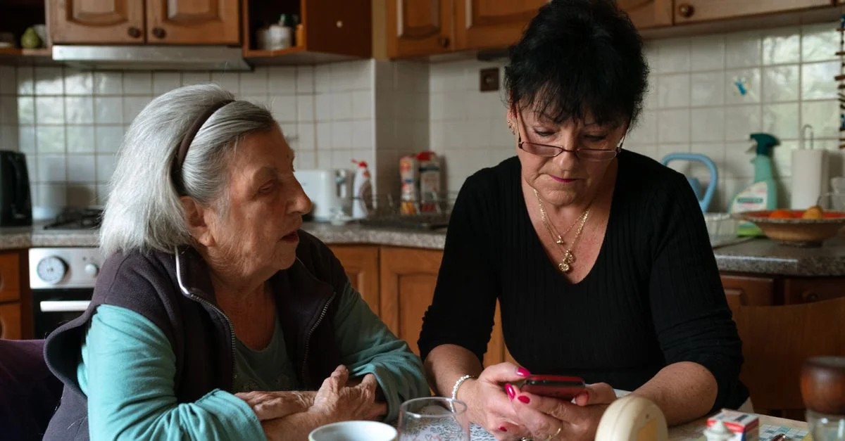 Une femme senior et un aidant partagent un moment dans un environnement chaleureux de cuisine familiale à Prague.