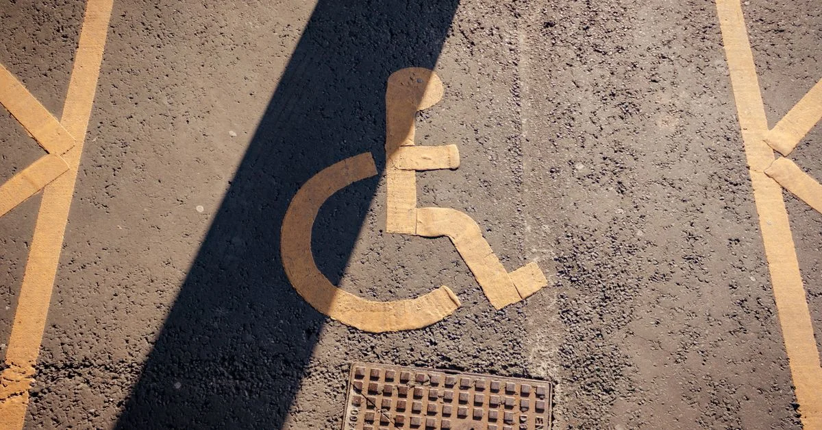 Gros plan d'un symbole de fauteuil roulant jaune peint sur l'asphalte, mettant en avant l'accessibilité.