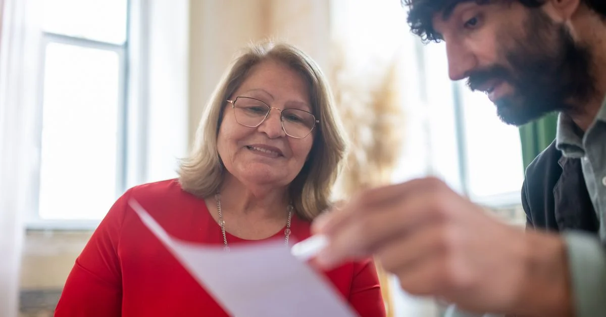Femme âgée et homme barbu lors d'une réunion de consultation examinant des documents à l'intérieur.