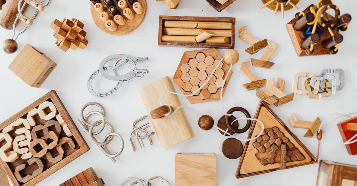 Vue de dessus de divers casse-têtes en bois sur une table blanche, mettant en avant des designs uniques et des défis ludiques.