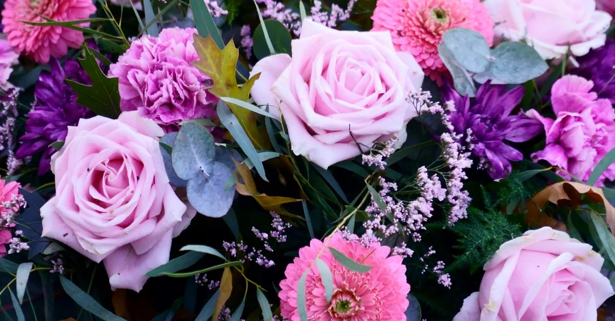 Un magnifique arrangement de roses roses et de fleurs violettes, parfait pour l'inspiration en décoration florale ou les idées de cadeaux.