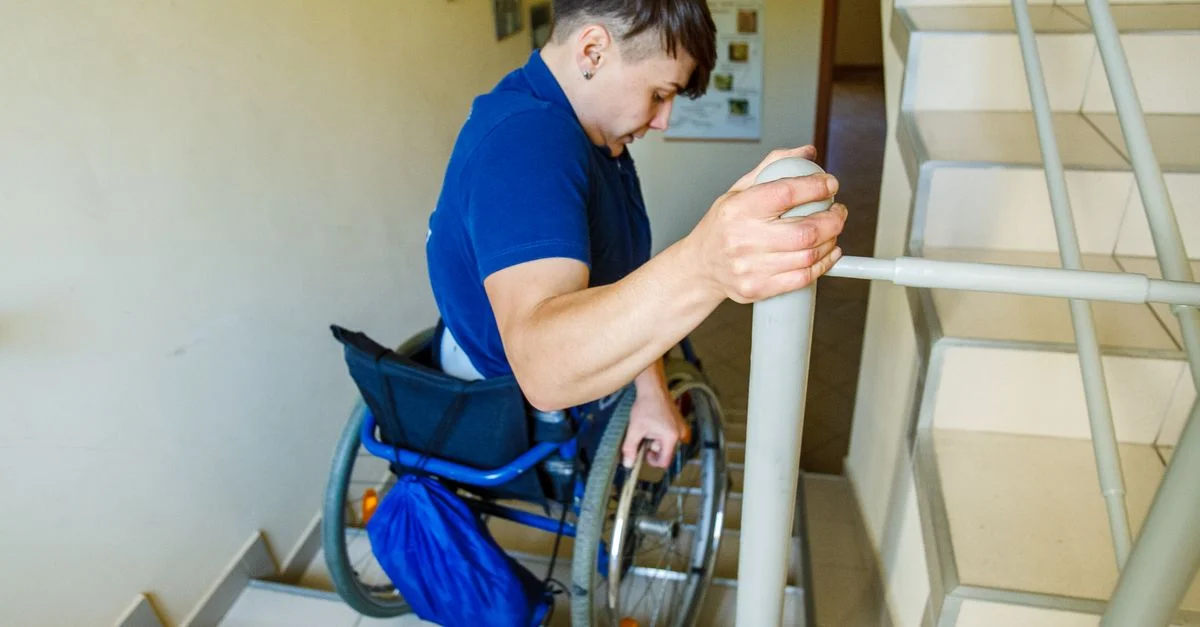 Homme confiant en fauteuil roulant naviguant un escalier intérieur, montrant de la détermination.