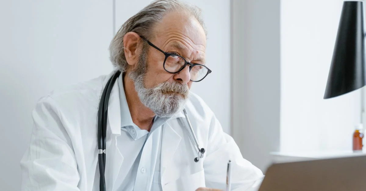 Médecin âgé utilisant la télémédecine pour une consultation virtuelle au bureau.