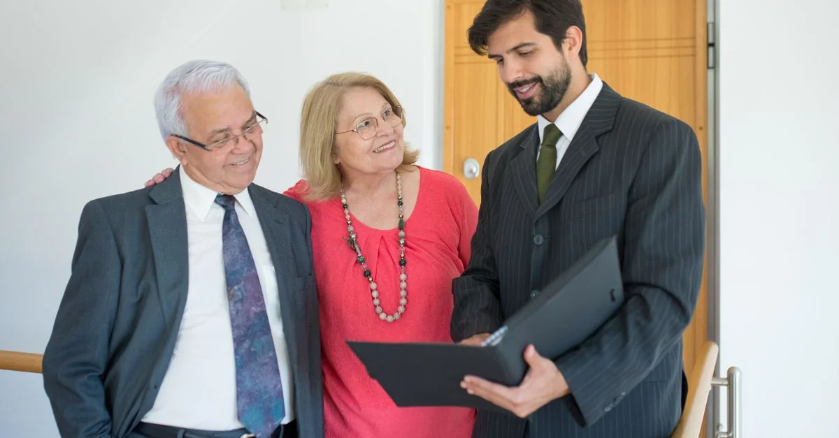 Un couple âgé rencontrant un agent immobilier à l'intérieur pour discuter de projets immobiliers.