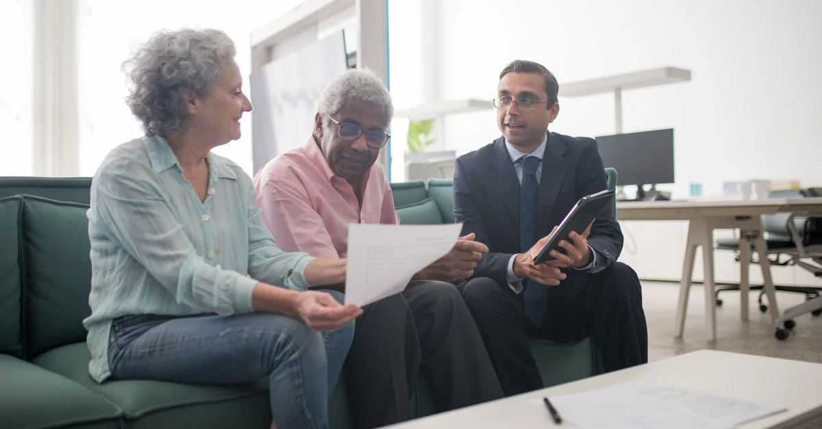 Couple senior discutant de documents avec un conseiller d'affaires dans un bureau moderne.