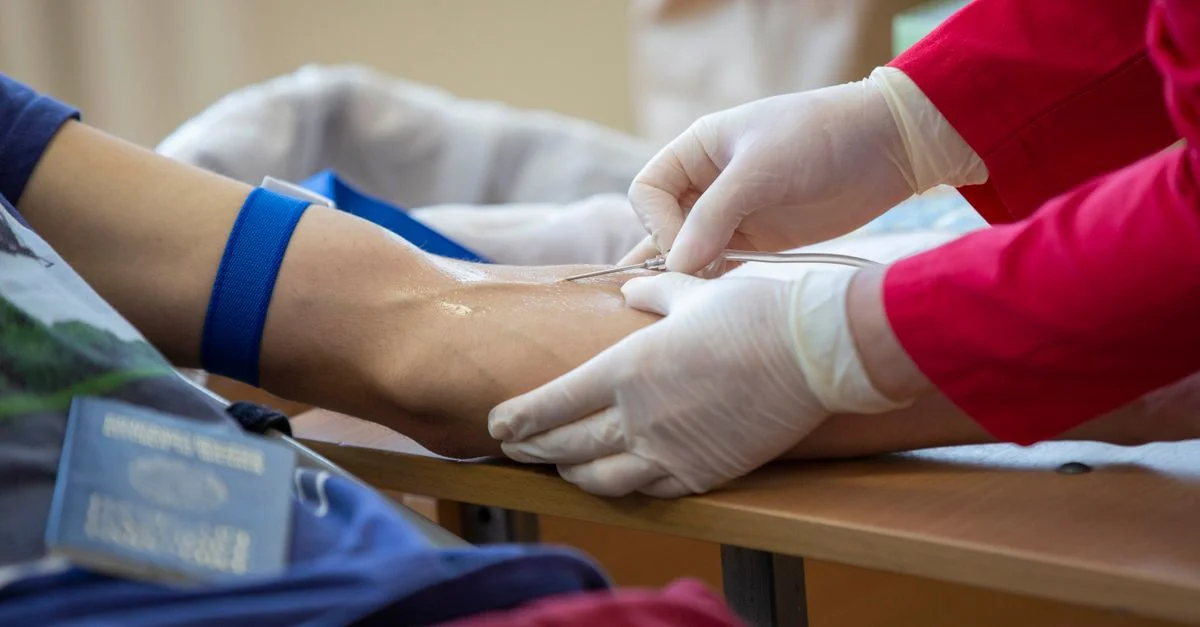 Professionnel de la santé prélevant du sang du bras d'un donneur dans un cadre clinique.