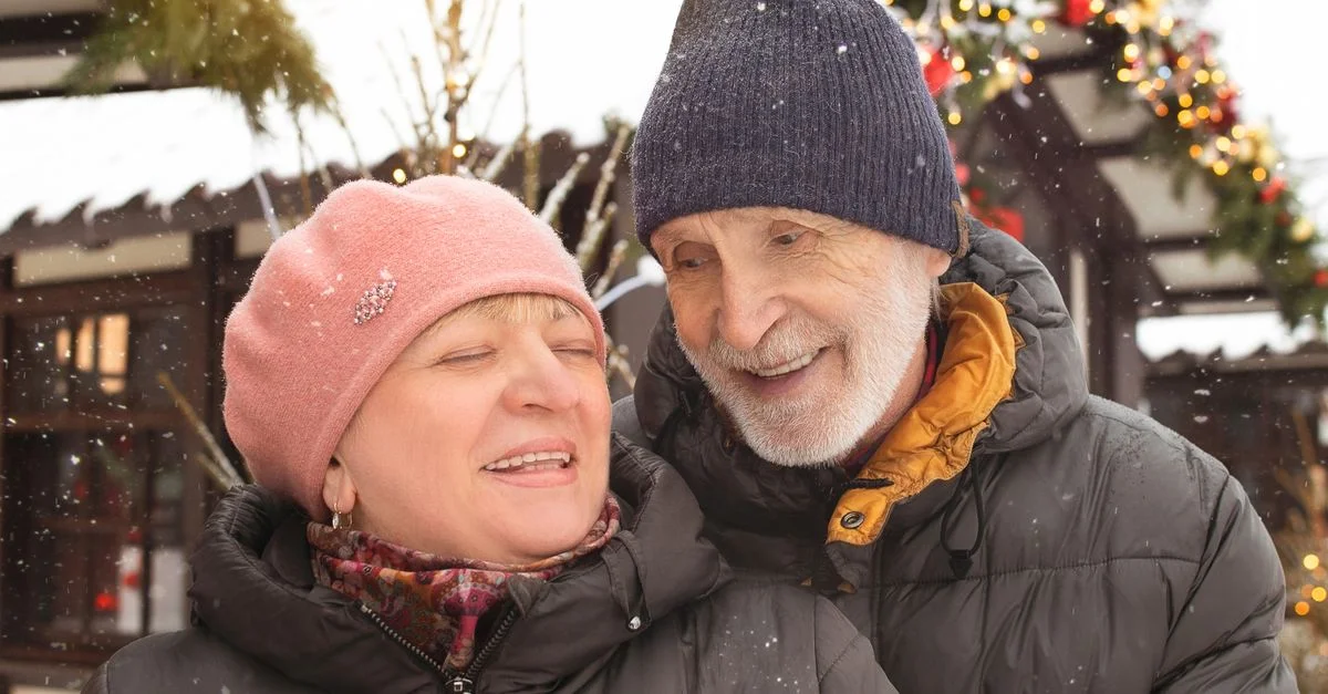 Couple âgé joyeux profitant d'une journée d'hiver enneigée en extérieur, habillés chaudement en vêtements d'hiver.