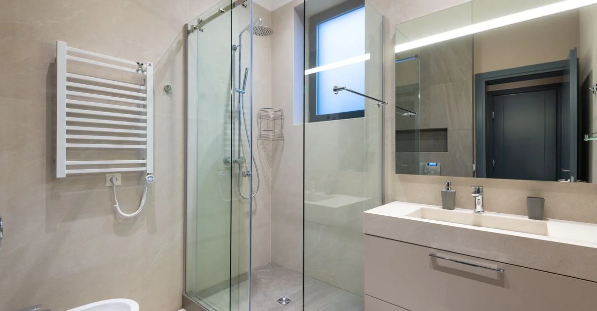 Intérieur de salle de bain contemporain avec douche en verre, lavabo et miroir dans des tons naturels.
