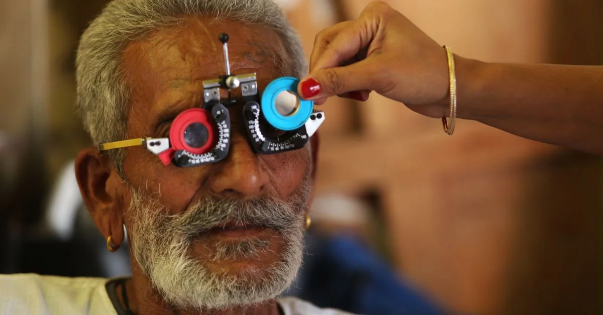 Homme senior subissant un test de vision avec un ensemble de lentilles d'essai lors de l'examen des yeux.