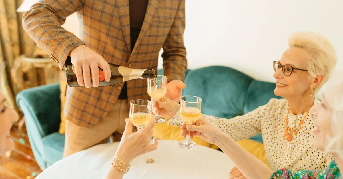 Des adultes seniors partageant un toast au champagne dans un cadre intérieur chaleureux.