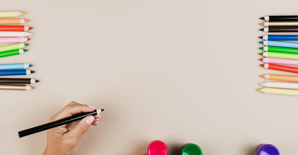 Plan de travail avec des crayons de couleur et de la peinture, offrant un bel espace pour le texte.