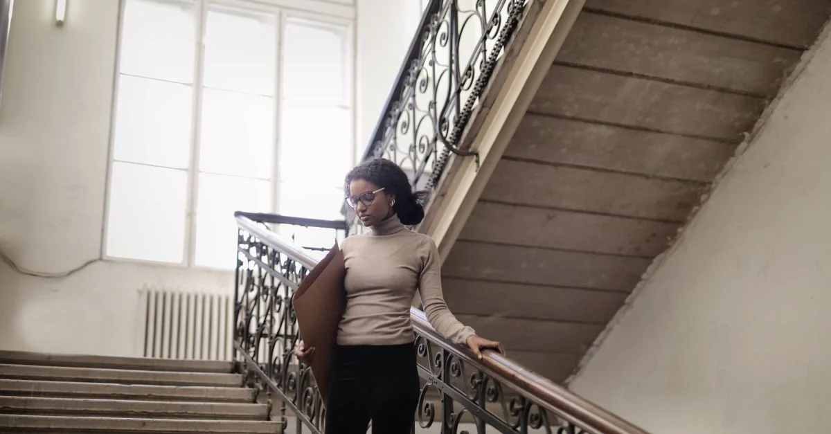 Femme élégante descendant un escalier magnifiquement orné à l'intérieur, dégageant de l'élégance.