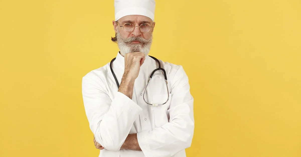 Portrait d'un médecin senior avec des lunettes et un stéthoscope sur fond jaune.