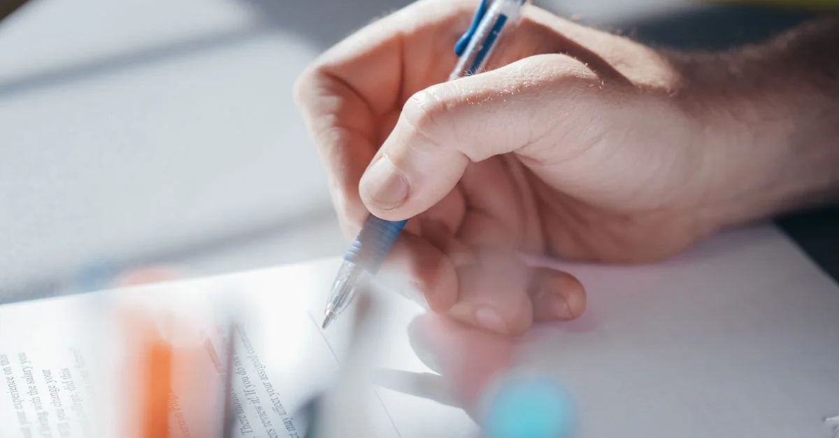 Plan rapproché d'une main écrivant avec un stylo, mettant en avant la concentration et la créativité.