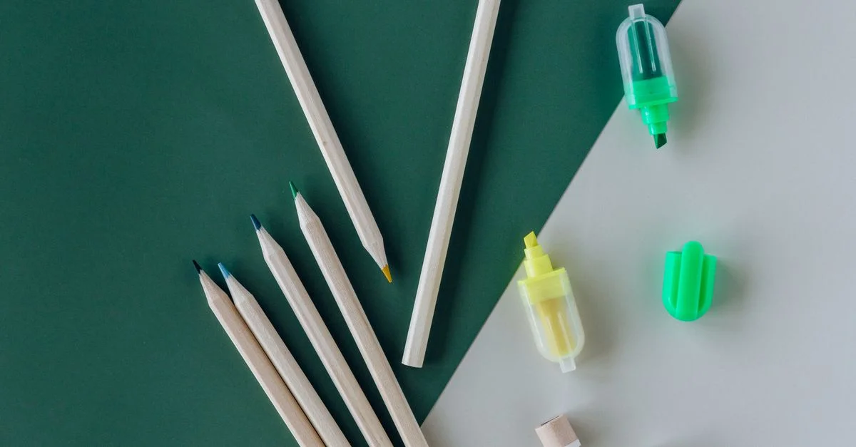 Fournitures artistiques comprenant des crayons et des surligneurs sur un fond vert et blanc, parfait pour des projets créatifs.