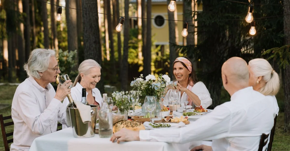 Groupe de seniors profitant d'un délicieux dîner en plein air avec rires et vin.